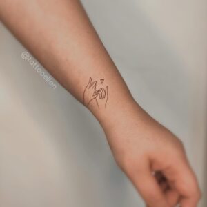 Tatuagem Minimalista de mãos entrelaçadas no braço
