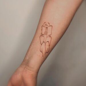 Tatuagem Minimalista de pessoa com livro no antebraço