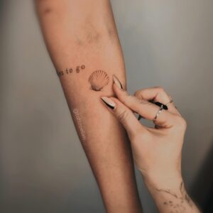 Tatuagem Minimalista frase e concha no braço