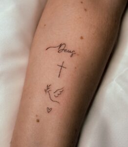 Tatuagem Minimalista cruz pomba e coração no braço