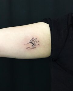 Tatuagem Minimalista de maos entrelacadas no braco