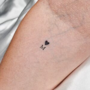 Tatuagem Minimalista coração com letra no braço