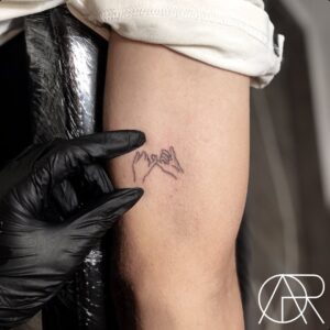 Tatuagem Minimalista de mãos entrelaçadas no braço