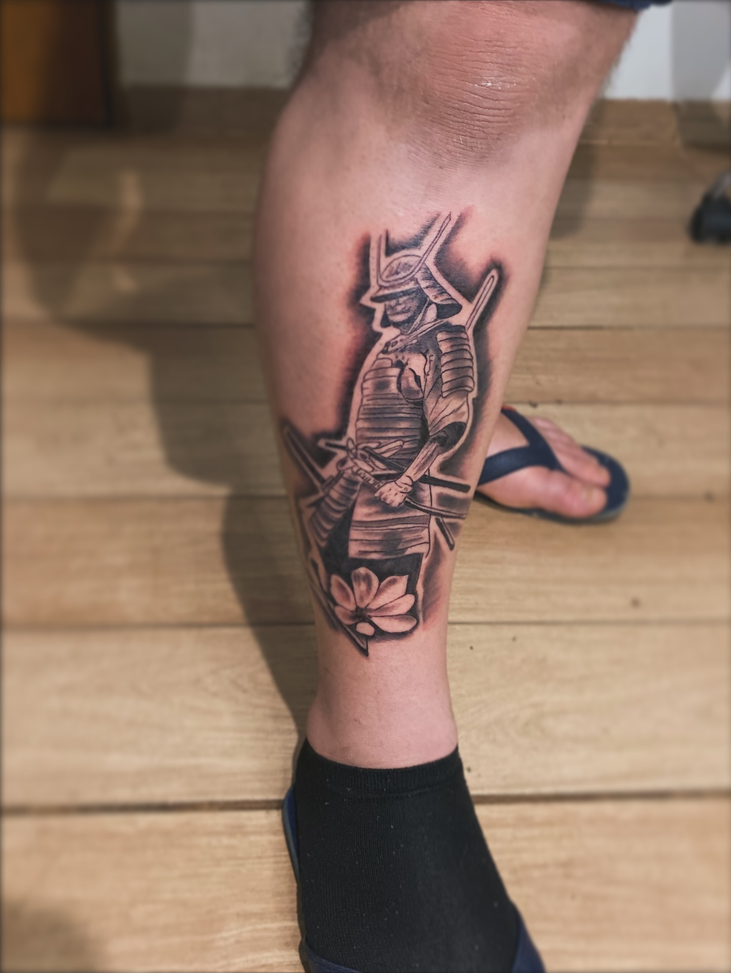 Tatuagem Samurai em pé com flor no tornozelo