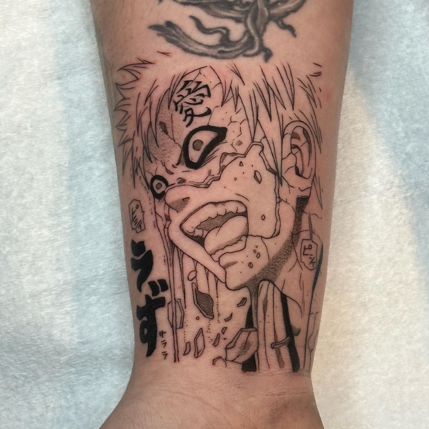 Tatuagem do Gaara com o rosto expressivo no antebraço