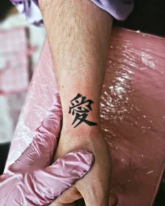 Tatuagem do Gaara com símbolo em escrita estilizada no braço